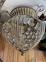 Close up image of the top of the chandelier showing intricate brass frame and crystal embellishments, demonstrating ornate and bling design