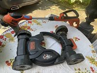 Black & Decker cordless compact mower laid on table showing overall design including handle, shaft, and mower base with wheels.