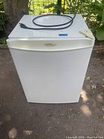 Closed front view of white Danby bar fridge with beige trim on top edge and logo on front.