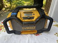 Front top view of well-used DeWalt radio with handle, control panel with buttons and dial visible