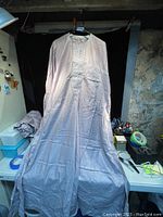 Long Nigerian traditional top hung for display, showing full length and drape of garment.