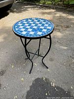 Full view of the round patio wine table showing the iron base and decorative porcelain tile top with blue and white pattern.