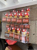 24 individually boxed Super Mario mushroom wine stoppers arranged in rows.