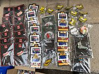 Photo shows 38 assorted metal enamel collector pins laid out on a surface. Includes multiple Zelda Tri-Force pins, Super Meat pins, and others including stylized smiley face and graphic designs, many on backing cards.