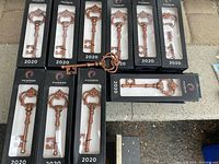 Fifty boxed metal key-shaped bottle openers with black packaging marked 2020. One key bottle opener out of box shown.