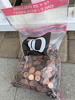 Clear zip-top plastic bag filled with approximately 2500 copper pennies, showing the quantity and condition of the coins.
