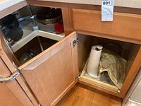 Photo of open corner under-counter cabinet showing paper towel holder and pots.