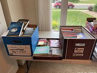 Photo showing two of the three boxes containing books including 'The Origin' by Dan Brown and several fiction and spiritualism books.
