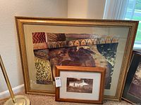 Photo of the large framed print showing the abstract composition with natural and animal motifs and gold frame, with smaller framed watercolor photo in front.