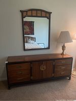 Dresser with nine drawers and two doors, brass hardware, dark wood trim, and overall wood finish showing wear.