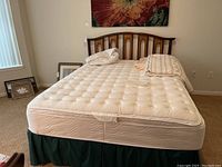 Front view of wooden headboard with attached rails, mattress and linens