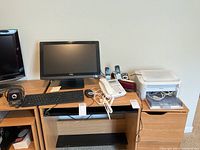 Front view of Dell 19-inch all-in-one computer, keyboard, wired and cordless phones, and Canon printer on desk.