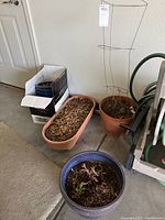 Six outdoor planter pots grouped showing terracotta, ceramic, and plastic materials with soil inside