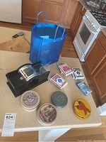 Image showing all items on a kitchen counter, including four decks of cards, four sets of coasters, and a blue tote bag in background.