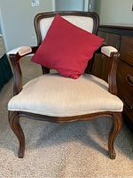 Front view showing upholstery and red throw pillow on the wooden framed chair.