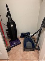 Overview of the two vacuums positioned next to each other on tile floor.