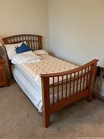 View of bed assembled with bedding and mattress showing solid wood twin bed frame and bedding details