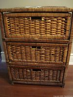 Front view of the 3 drawer wicker cabinet showing the woven drawer fronts and cut-out handles.