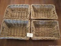 Four large rectangular wicker/rattan baskets arranged in a 2 by 2 grid on floor, showing overall shape and color.