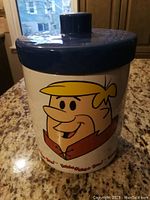 Photo showing the Barney Rubble face graphic on the cookie jar with lid on top, placed on countertop.