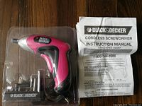 Photo showing Black & Decker cordless screwdriver in pink and black color, battery charger, 8 assorted bits, and instruction manual.