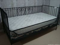 Full view of black metal daybed frame with mattress and box spring underneath, shows general condition and style.