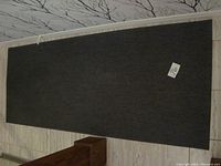 Full view of dark grey rectangular IKEA runner rug on floor, showing condition and size.