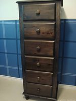 Front view of the tall lingerie chest showing six drawers with wooden knobs and turned feet at the base.