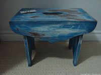 Front view of turquoise wood stool showing distressed paint and handle cutout