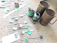 Photo showing an assortment of silver spoons with various purity stamps, two small Mexican containers, and a letter opener, all displayed on carpet.