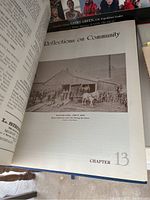 Photo of an open book showing a chapter titled 'Reflections on Community' with a black and white farm photo from about 1910 depicting heavy horses in use during harvest