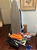 Ironing board, vacuums parts, towels, and cleaning supplies on the floor