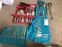 Overview of flatware assortment on carpet showing cloth rolls and loose utensils