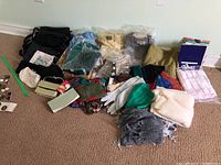 Wide view of the whole lot showing sweaters, scarves, gloves, and handbags arranged on floor