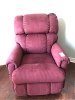 Frontal image of the burgundy fabric recliner chair with cushioned back and armrests, showing overall shape and condition.