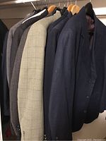 Photo showing six men's jackets hanging, varying in shades of blue, black, gray and beige, all approximately size 42R.