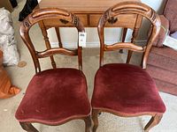 Pair of carved wooden occasional chairs with wine-colored upholstered cushion seats, front view showing carved backs and cushioned seats
