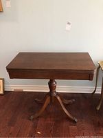 Full view of the wooden occasional table top and base showing the rectangular top and pedestal support.