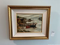 Framed oil painting showing entire artwork with coastal scene, dock, boats, and background trees.