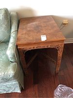 Side view showing rectangular wooden table next to a sofa, carved apron and legs with geometric floral cut-outs.