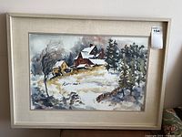 Framed watercolour print showing a winter scene with houses and trees, with visible frame and matting.
