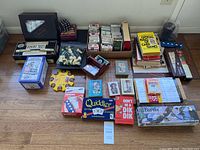 Overview photo showing a large assortment of games, dice, cards, puzzles, and books arranged on a floor.