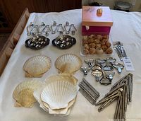 Full layout of assorted seafood culinary tools including crackers, escargot holders, tongs, and natural shells on white surface.