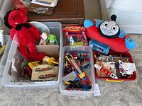 Overview of bins containing assorted toys including a large red stuffed dog, a green turtle toy, smaller stuffed toys, and bins with various LEGO pieces and builds.