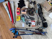 Overview of all items in lot including umbrellas, trekking poles, grabbers, shoehorns, tripod seat, and assorted accessories spread out on floor.