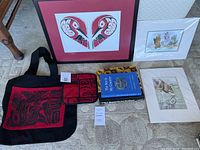 Overview photo showing framed art, matted prints, tote bag, pot holder, and books.