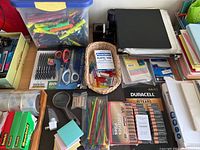 Overview of office supplies including batteries, scissors, plastic tabs, sticky notes, zip ties, magnifying glass, and file folders.