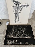 Two prints displayed: one abstract standing figure in black ink on cream, one detailed sailing ship sketch in white on black