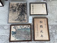 Overall view of four framed pieces on carpet showing different styles and subjects