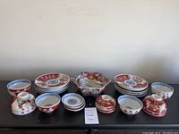 Photo of entire set showing plates stacked left and right, bowls in front, large hexagonal dish with several spoons in center